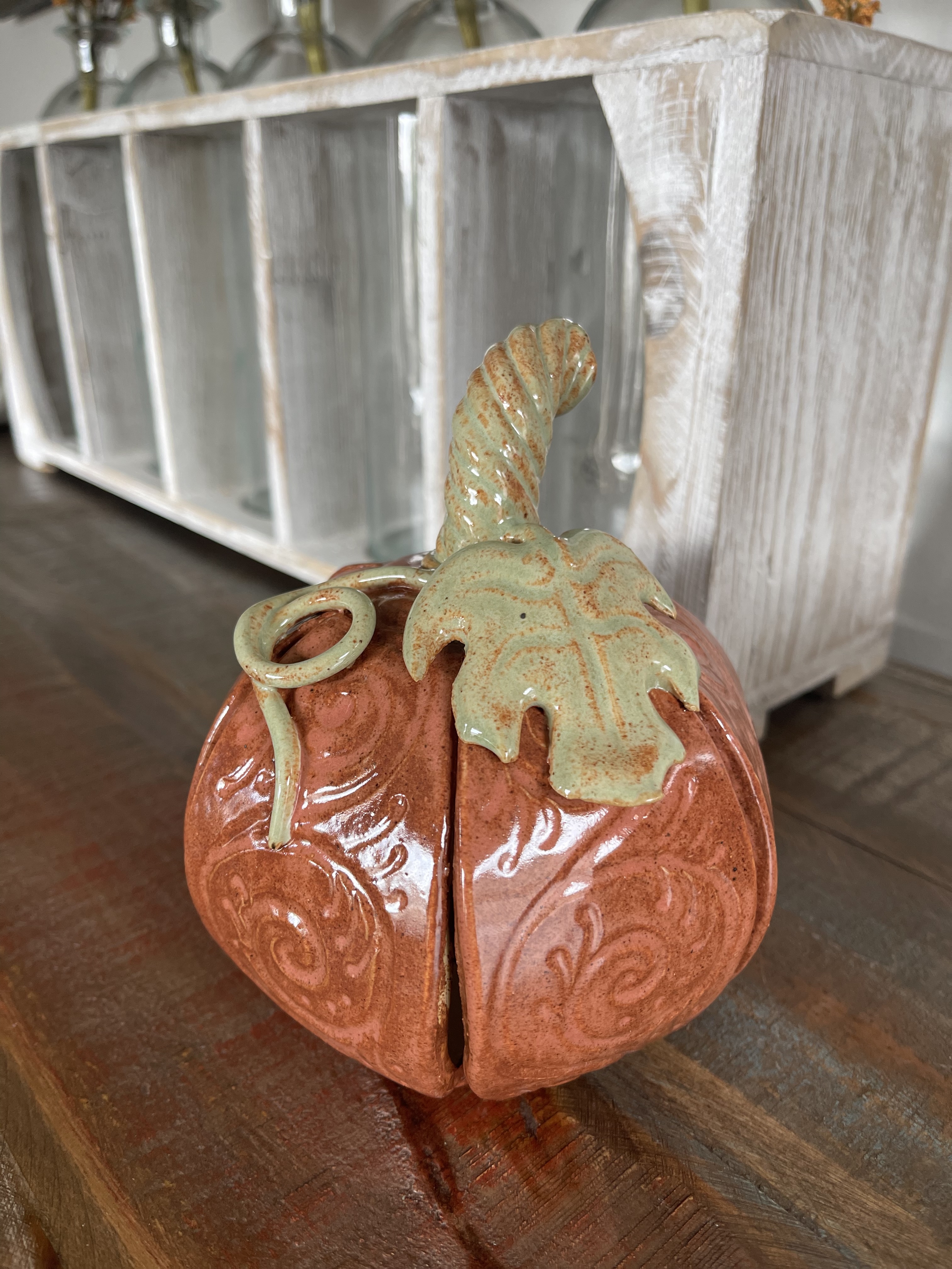 Alternate view of the orange ceramic pumpkin showing its raised filigree and sculpted leaves