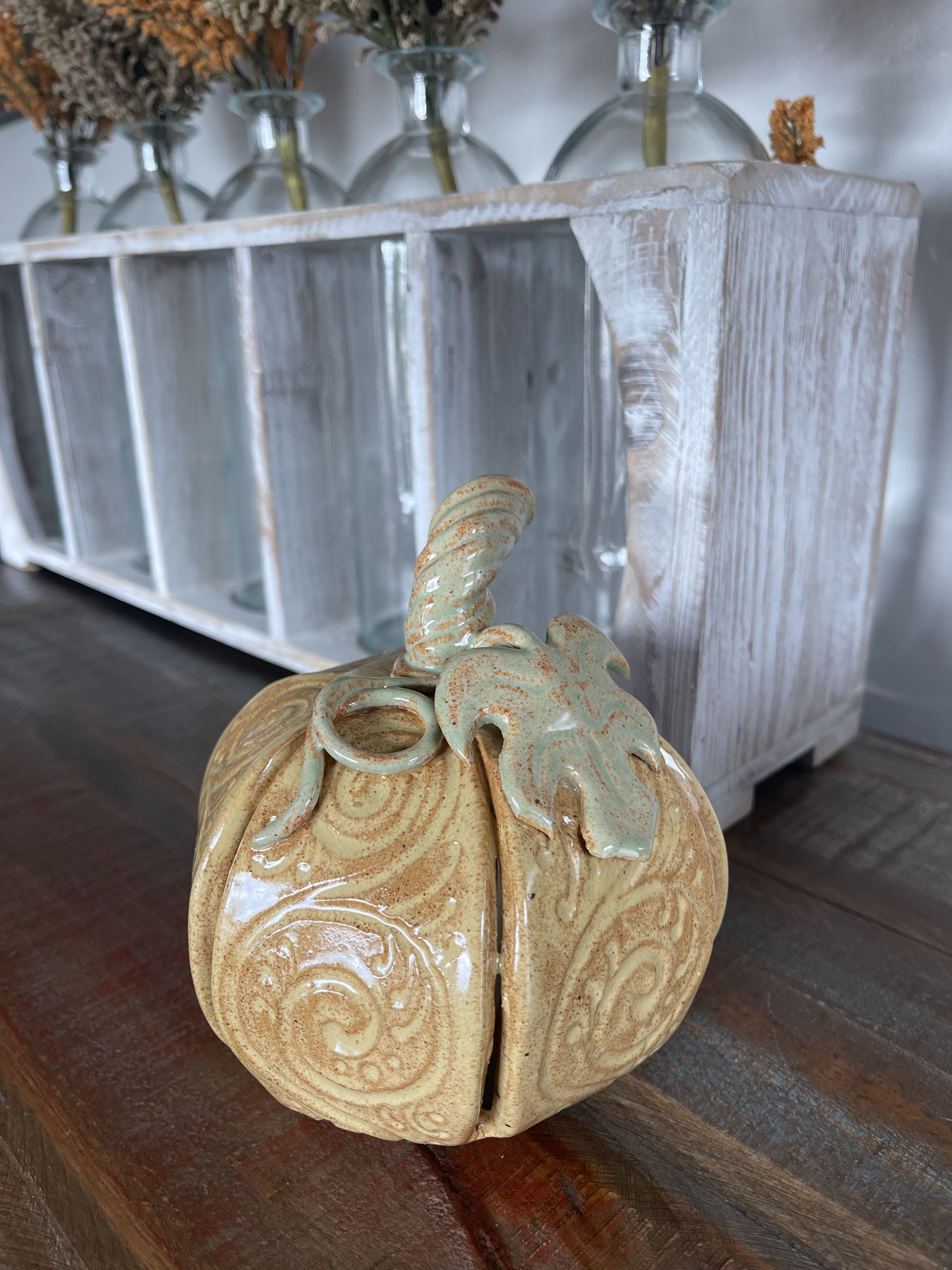 Yellow filigree ceramic pumpkin displayed on a wooden surface