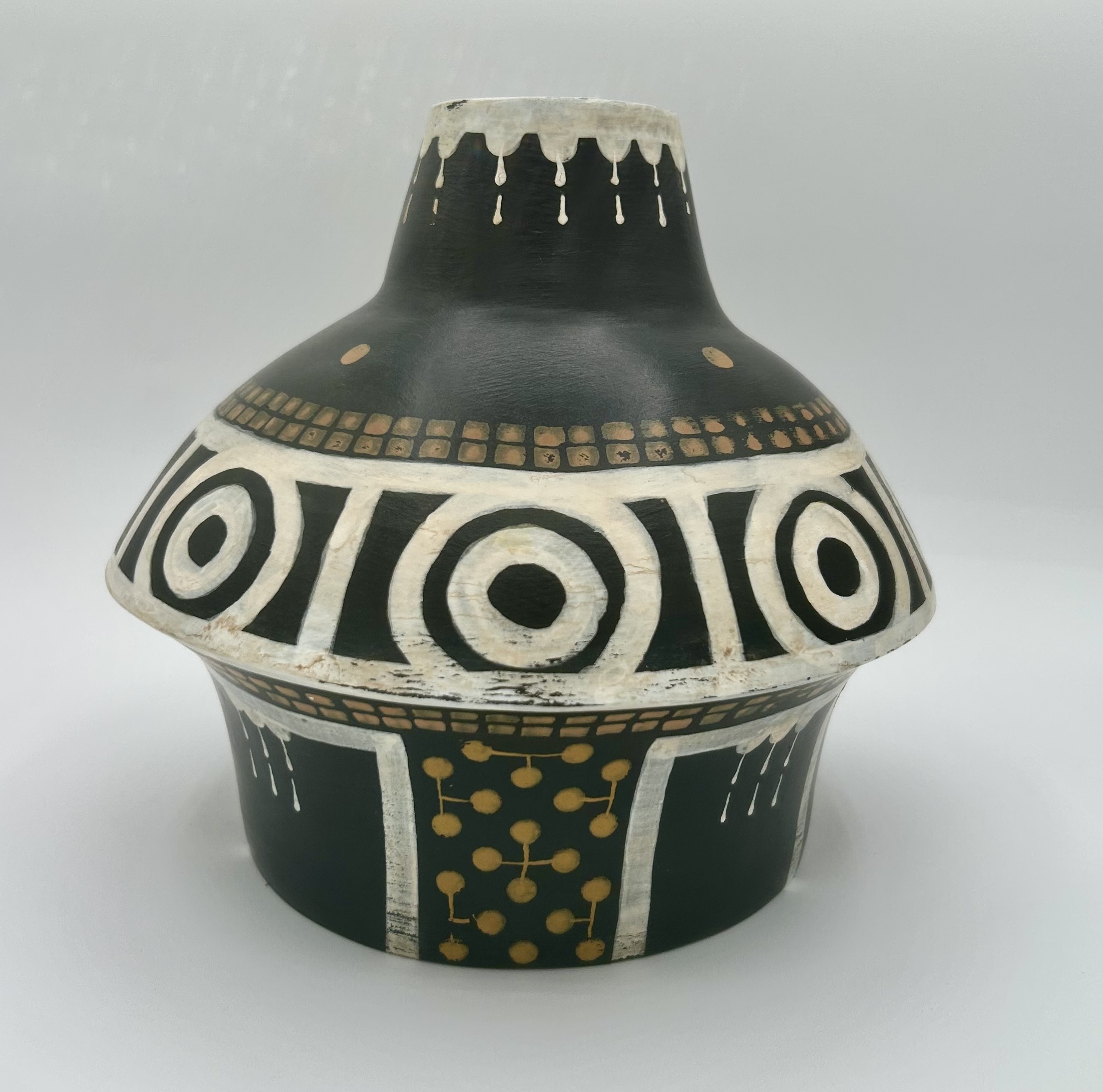 Studio view of a black ceramic jug with white geometric bands and yellow dots